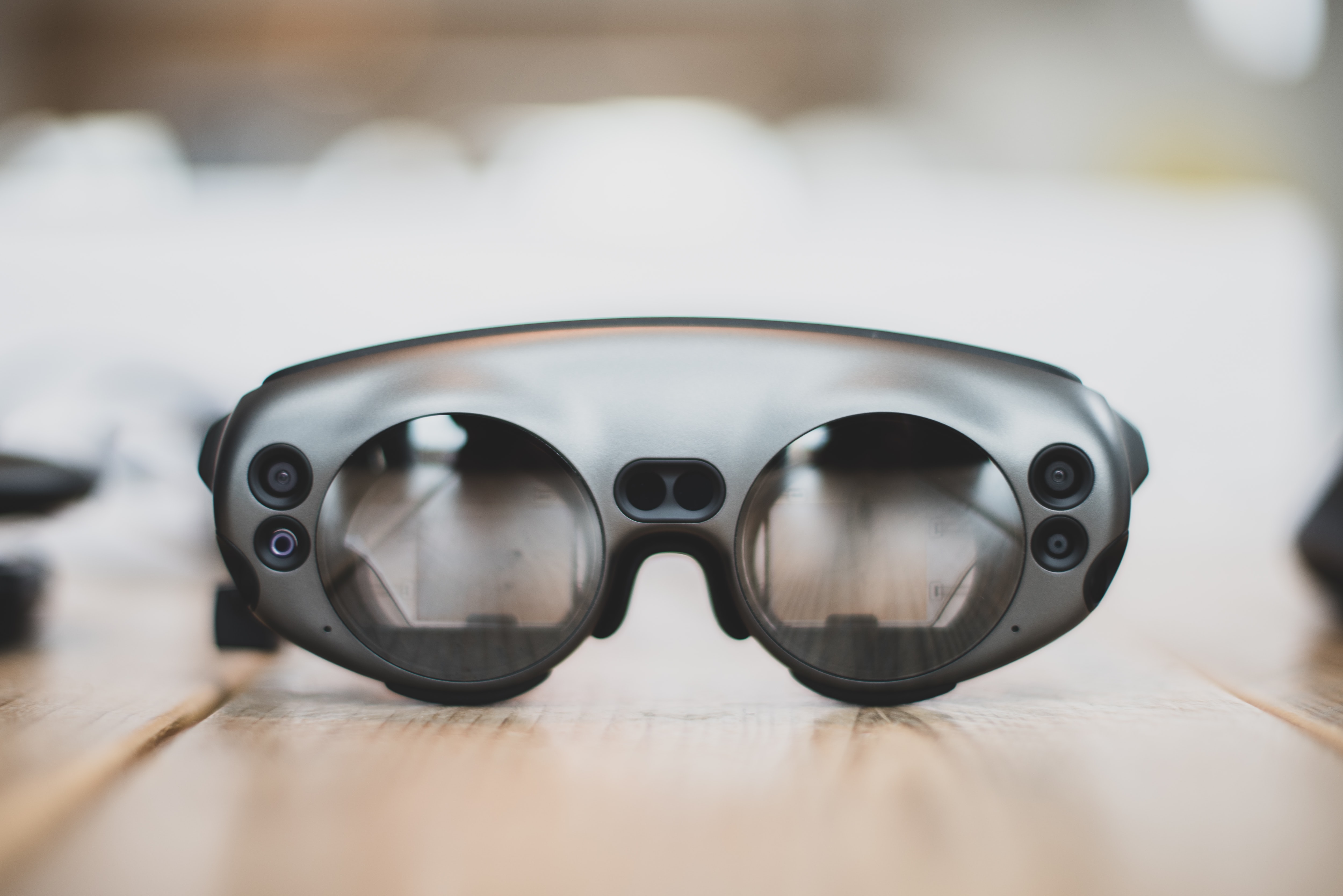 A pair of google glasses sitting on the table made of fine, pale pine wood.